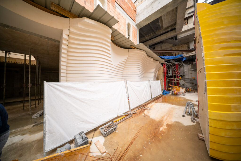 Architettura delle cantine vinicole: casseforma su misura armata in cantiere per realizzare muri a gradoni curvilinei in calcestruzzo con getto a vista per cantina vinicola in Francia 