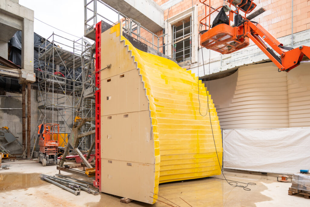 Architettura delle cantine vinicole: casseforma su misura armata in cantiere per realizzare muri a gradoni curvilinei in calcestruzzo con getto a vista per cantina vinicola in Francia 